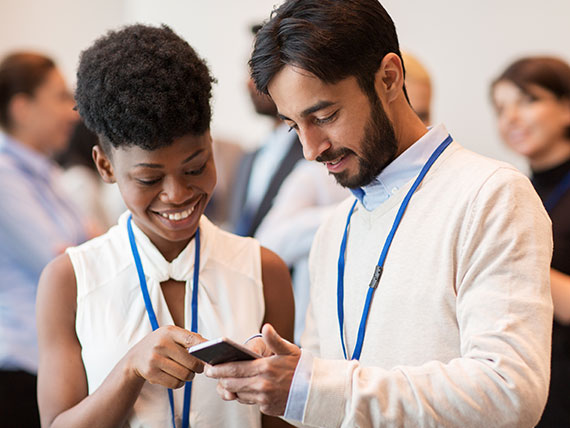 Male and female students wearing conference badges looking at phone